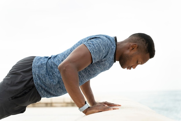 Healthy active man with fit muscular body doing push ups exercises