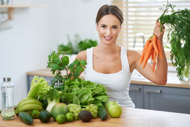 healthy adult woman with green food in the kitchen