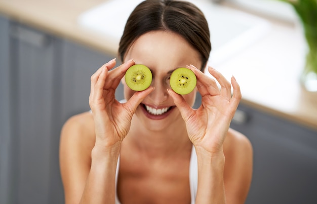 healthy adult woman with green food in the kitchen