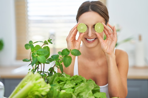 healthy adult woman with green food in the kitchen