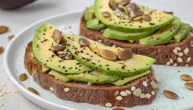 Healthy avocado toasts for breakfast or lunch with rye bread sliced avocado and pumpkin seeds