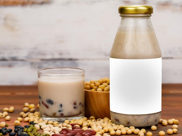 Healthy bean milk of vegetarian breakfast for nourishment and refreshment drink mixed with natural organic legume grain. Liquid extract in glass cup and bottle as advertising beverage product.