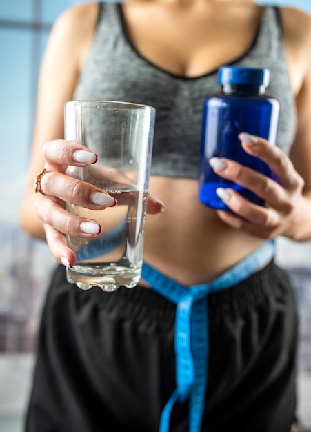 Healthy beautiful young woman holding a glass of water to ask for vitamins for weight loss hands with a glass of water vitamins for weight loss