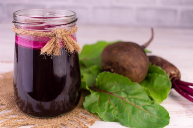 Healthy beetroot smoothie in a jar on a white wooden background.