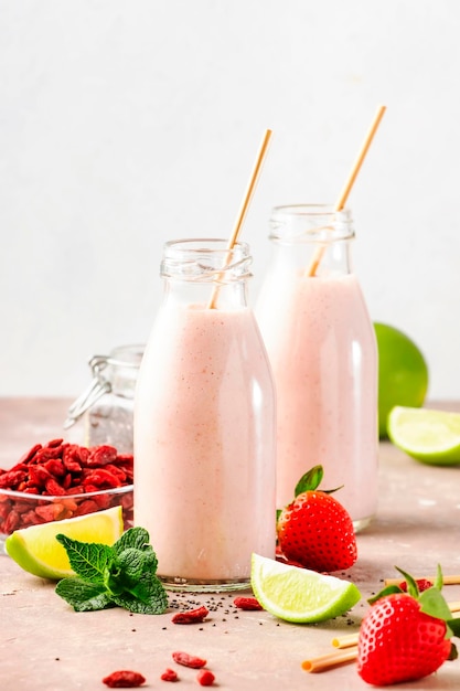 Healthy blended diet smoothie drink with strawberry and goji berries chia seeds and lime Glass bottles with eco fendley straws