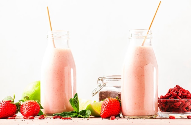 Healthy blended diet smoothie drink with strawberry and goji berries chia seeds and lime Glass bottles with eco fendley straws