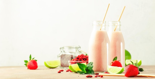 Healthy blended diet smoothie drink with strawberry and goji berries chia seeds and lime Glass bottles with eco fendley straws