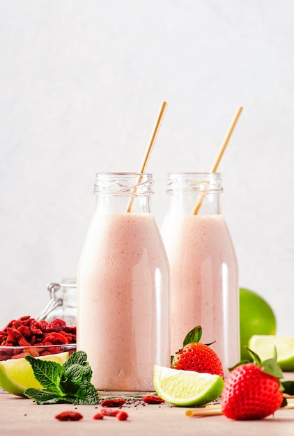 Healthy blended superfood drink Organic diet smoothie with strawberry and goji berries chia seeds and lime Glass bottles with eco fendley straws Gray background with copy space