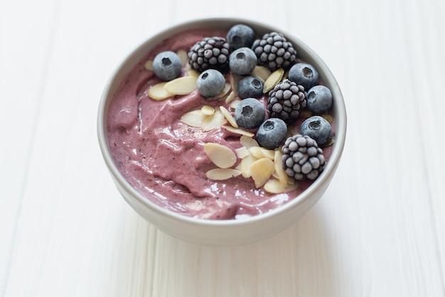 Healthy breakfast berry smoothie bowl topped with banana, granola, Blueberries and chia seeds with 