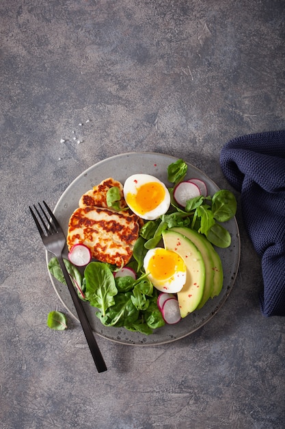 Healthy breakfast: boiled egg, avocado, halloumi cheese, salad leaves