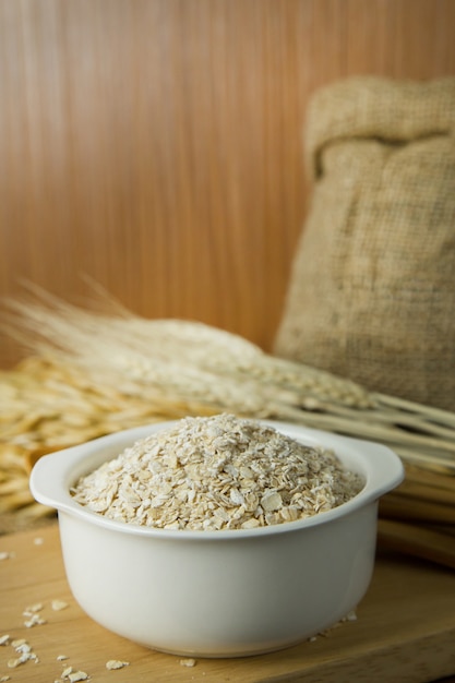 The Healthy breakfast cereal oat flakes in bowl on wooden table