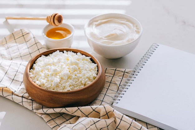 Healthy breakfast of cottage cheese with sour cream and honey, clean blank for your text, diet plan on a marble table