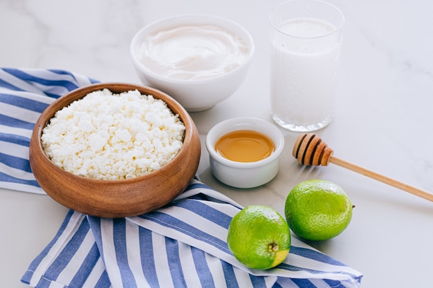 Healthy breakfast of cottage cheese with sour cream, honey and lime on a marble table