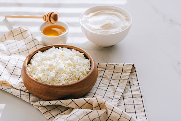 Healthy breakfast of cottage cheese with sour cream and honey on a marble table