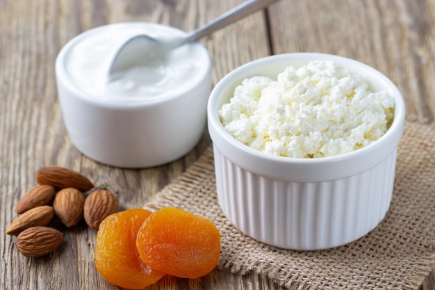 Healthy breakfast. Ð¡ottage cheese, cream sour, nuts and dried apricots on wooden rustic table.