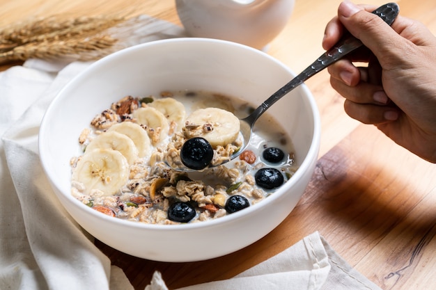 Healthy breakfast. Fresh granola, muesli with milk , bluberries and banana on wooden table.