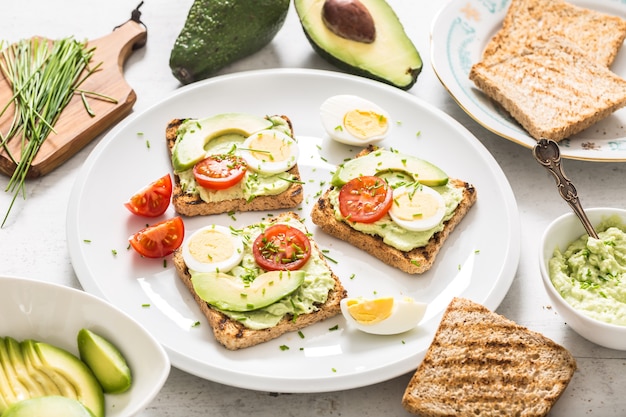 Healthy breakfast from toasts with avocado spread guacamole egg tomato and chives.