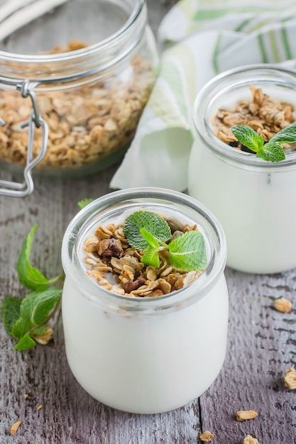 Healthy breakfast. Homemade oat granola with greek yogurt and mint leaves on wooden background