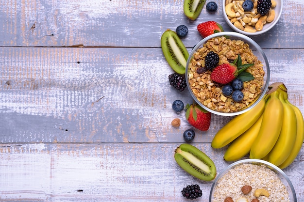 Healthy breakfast ingredients. Muesli, nuts, fruits, berries, banana on wooden rustic background.