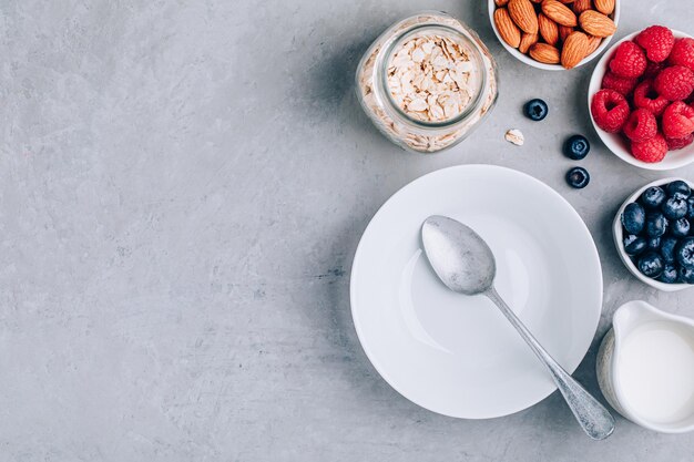 Healthy breakfast Ingredients for oatmeal Blueberries strawberries almonds milk and oats Top view copy space