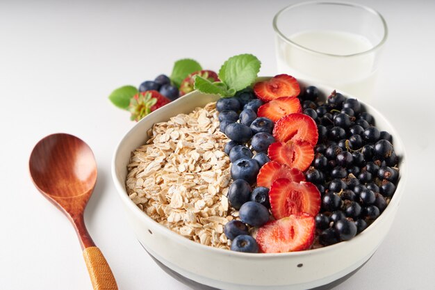 Healthy breakfast, muesli with currants, blueberries and strawberries served in bawl on light space