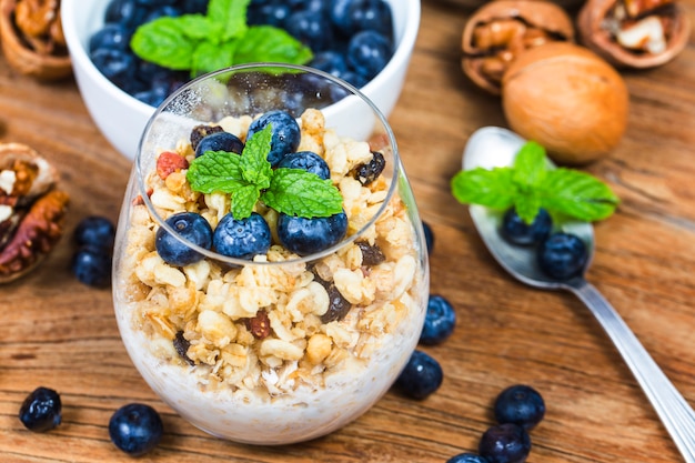 Healthy breakfast: oat granola with yogurt and fresh blueberries on wooden background