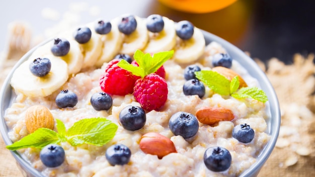 Healthy breakfast Oatmeal porridge with berries fruits and honey on dark background