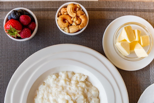 Healthy breakfast. Rice porridge bowl with berries and nuts on the table, hot and healthy breakfast food, top view