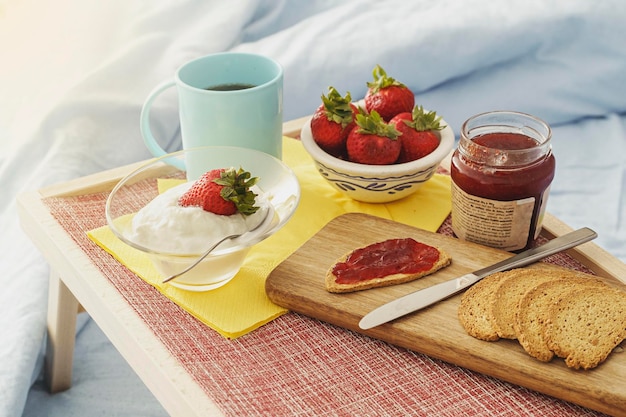 Healthy breakfast served in bed tray with fruit yogurt juice and coffee to eat between the blankets healthy lifestyle concept