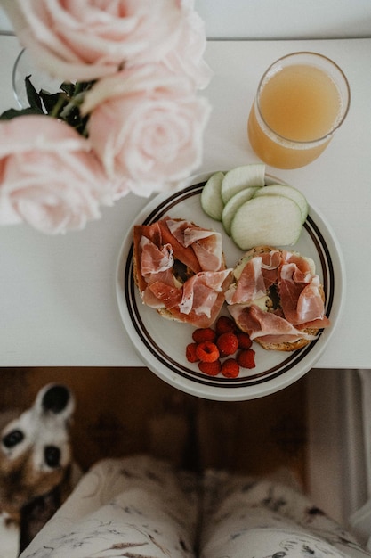 Healthy breakfast on side table next to bed, with flowers and a cute dog