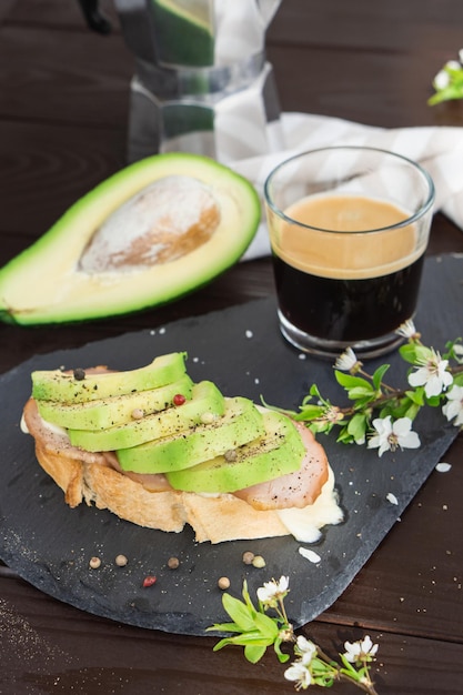 Healthy breakfast Toasted grain bread with fresh sliced avocado ham cheese and cup of coffee