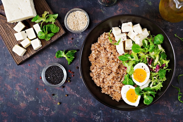 Healthy breakfast with egg, cheese, lettuce  and buckwheat porridge on dark background. 