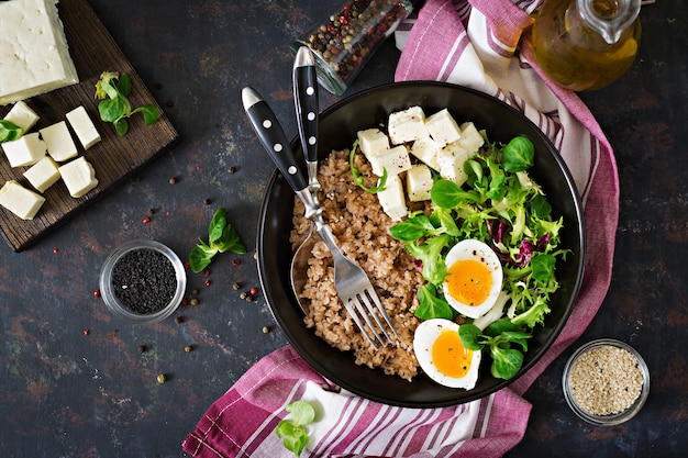 Healthy breakfast with egg, cheese, lettuce  and buckwheat porridge on dark background. 