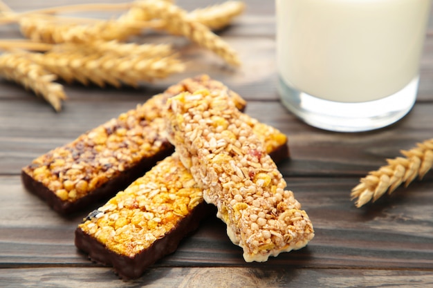 Healthy breakfast with granola bars and milk on brown wooden table.