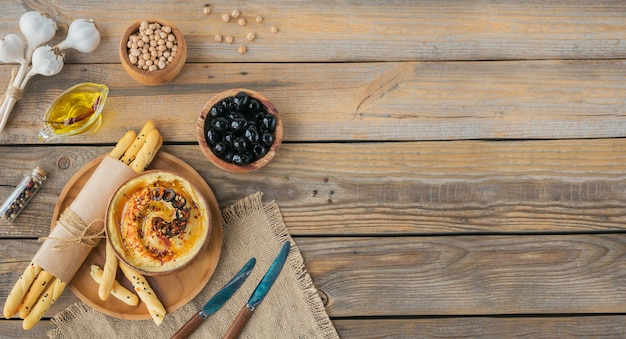 Healthy breakfast with homemade hummus, black olives and crispbread on wooden surface. Diet and Healthy snack food.