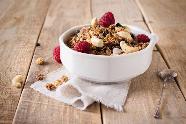 Healthy breakfast with oats granola,raspberry and nuts over wooden table