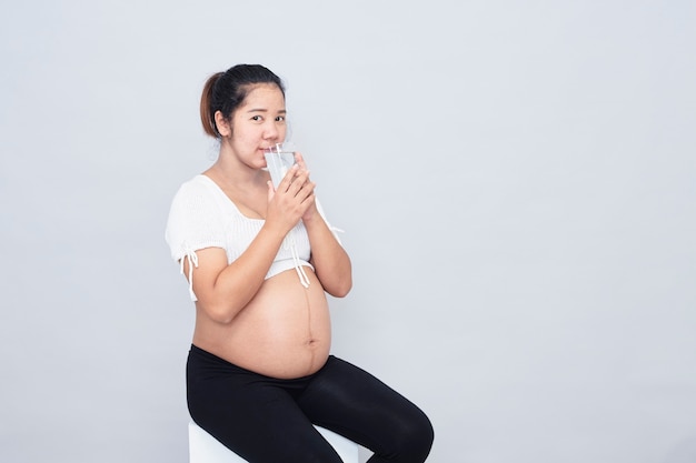 Healthy Calcium Drink. Pregnant young asian woman sitting Healthy Calcium Drink. Pregnant young Asian woman sitting holding a glass of milk