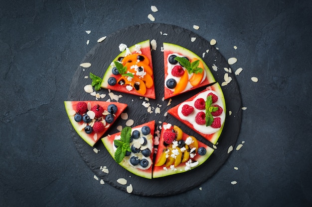 Healthy clean eating, dieting and nutrition, seasonal, summer concept. Watermelon pizza with berries, fruits, yogurt, feta cheese on a table. Top view flat lay copy space background.