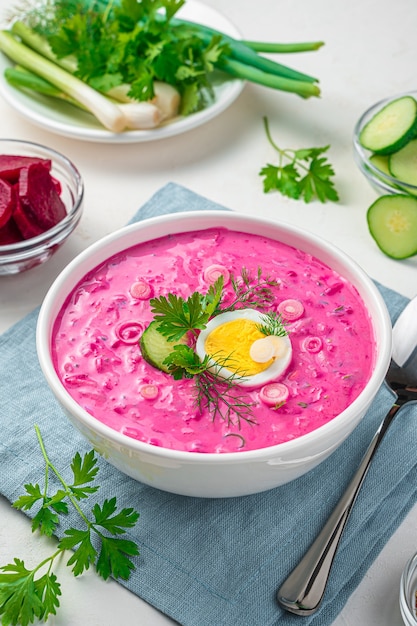 Healthy cold beetroot soup with egg on a light gray background. Vertical view.