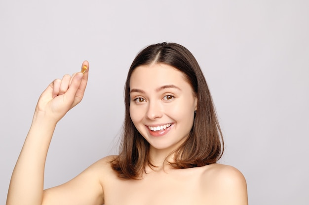 Healthy Diet Nutrition. Beautiful Smiling Young Woman Holding Fish Oil Pill In Hand