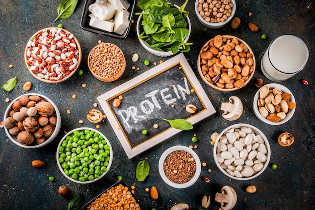 Healthy diet vegan food, veggie protein sources: Tofu, vegan milk, beans, lentils, nuts, soy milk, spinach and seeds. Top view on white table.