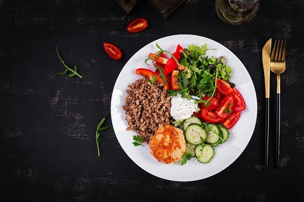 Healthy dinner Lunch bowl with buckwheat porridge fried chicken cutlet and fresh vegetable salad Top view flat lay