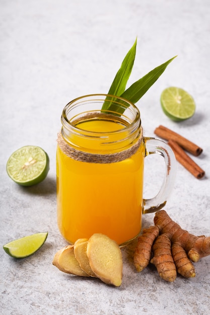 Healthy drink from turmeric and ginger roots and lime in a glass on white background.