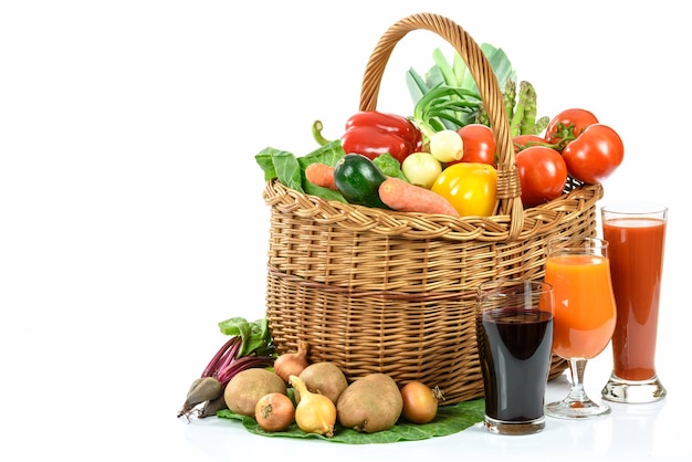 Healthy eating concept basket full of varied vegetables and various vegetable juices in glasses on white background