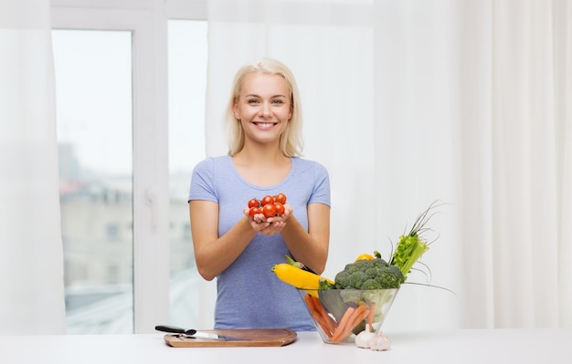 healthy eating, cooking, vegetarian food, dieting and people concept - smiling young woman with bowl of vegetables at home