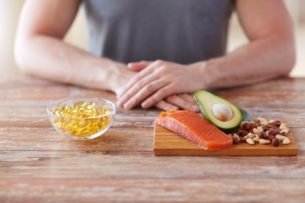 healthy eating, diet and people concept - close up of male hands with food rich in protein on cutting board on table