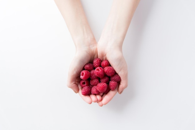 healthy eating, dieting, vegetarian food and people concept - close up of woman hands holding raspberries at home