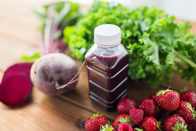 healthy eating, food, dieting and vegetarian concept - close up of bottle with beetroot juice, fruits and vegetables on wooden table