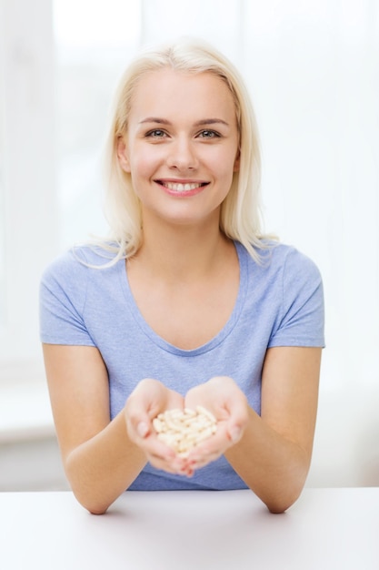 healthy eating, medicine, health care, food supplements and people concept - happy woman holding pills or capsules at home