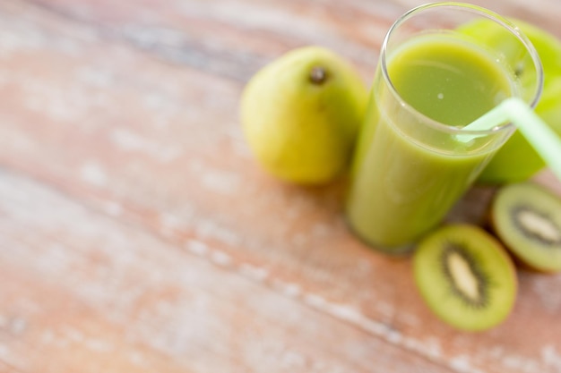 healthy eating, organic food and diet concept - close up of fresh green juice glass and fruits on table